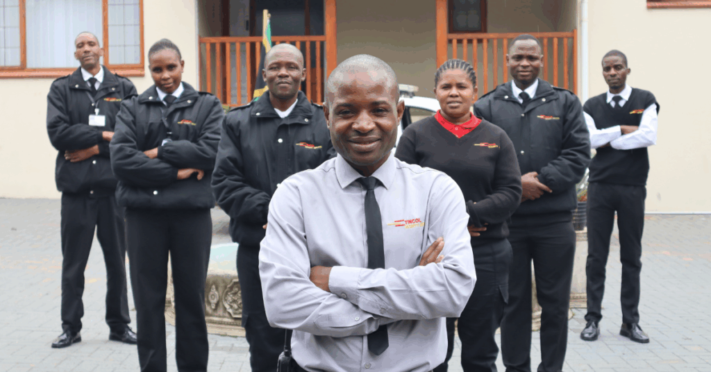 Team of professional security guards and personnel standing in formation outside a building, wearing Tincol Security uniforms.