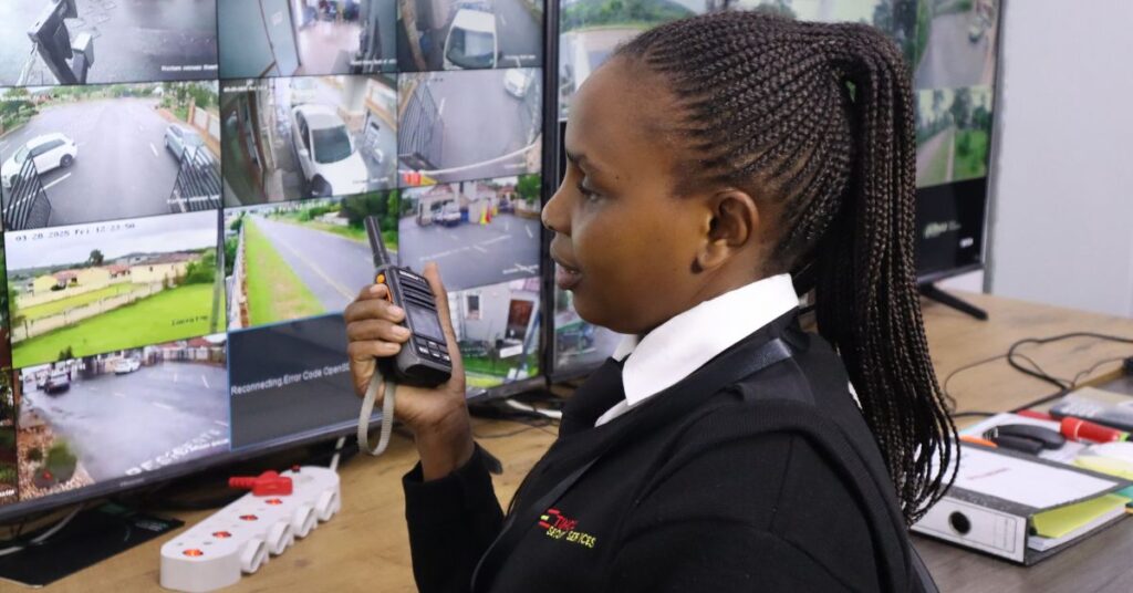Security control room operator monitoring multiple CCTV screens while communicating on a two-way radio.